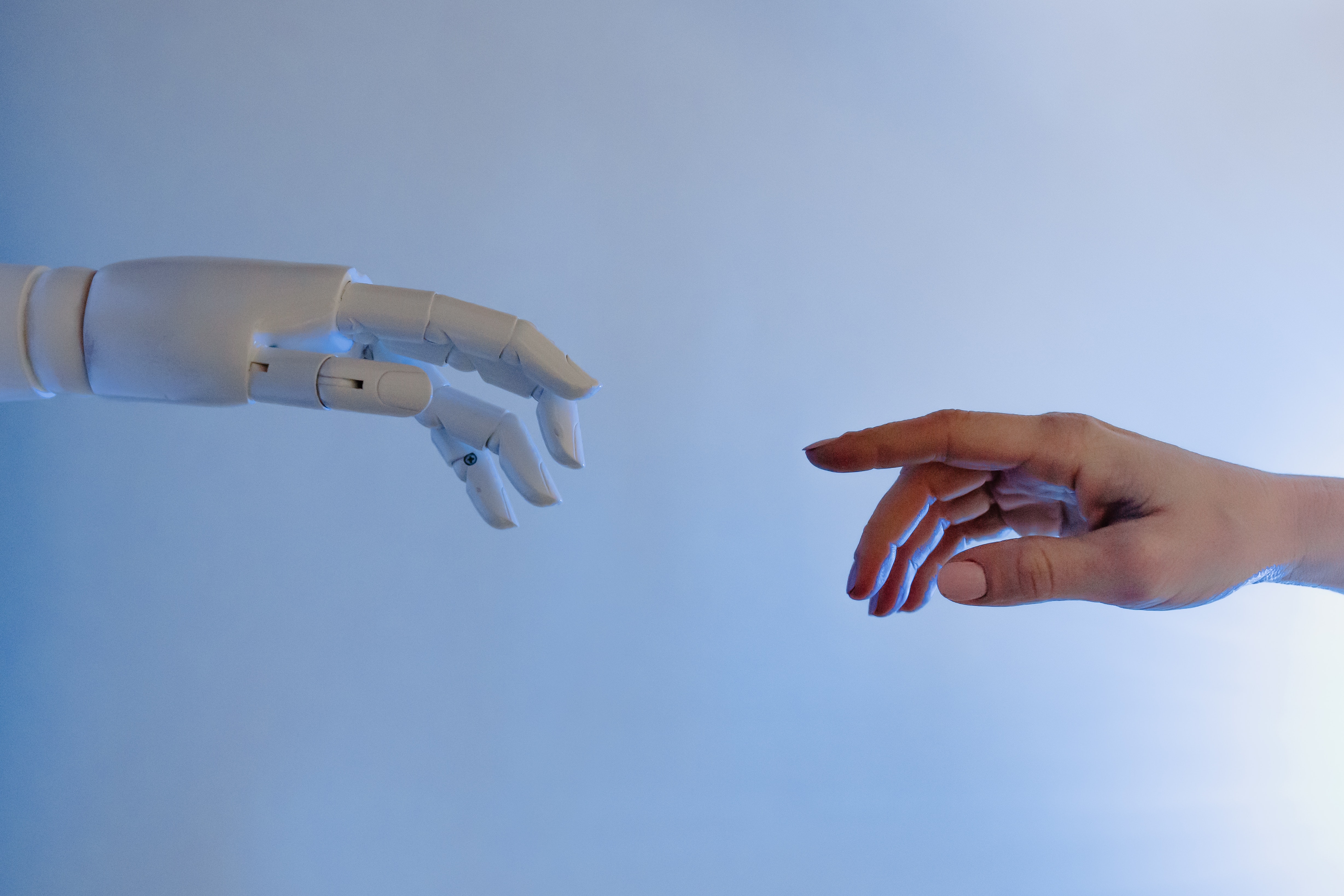A decorative image of a robot and a human hand approaching each other.
